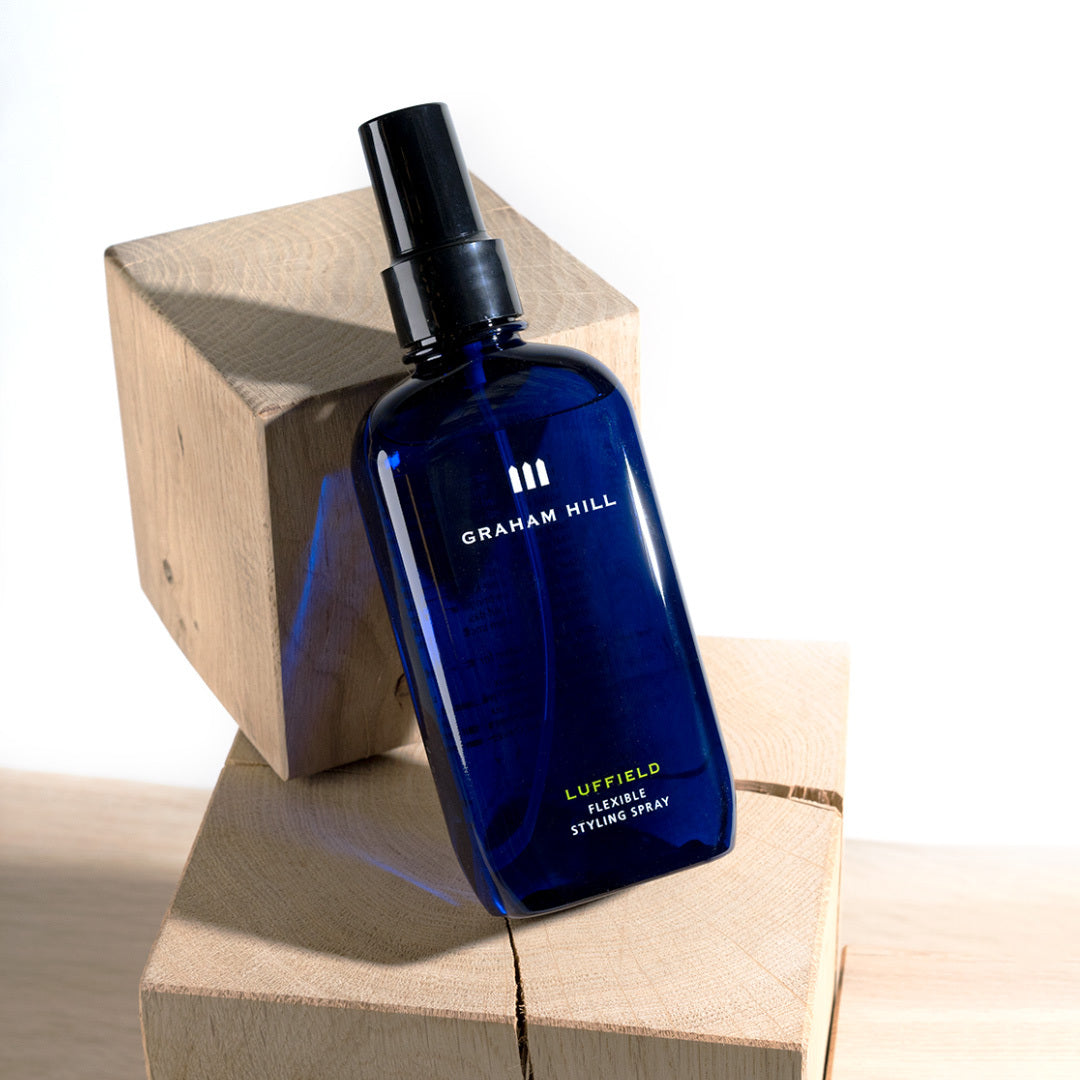 GRAHAM HILL LUFFIELD Flexible Styling Spray bottle resting against wooden blocks.